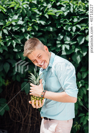cheerful emotional guy holding a pineapple. cheerful emotional guy holding a pineapple. 40718227