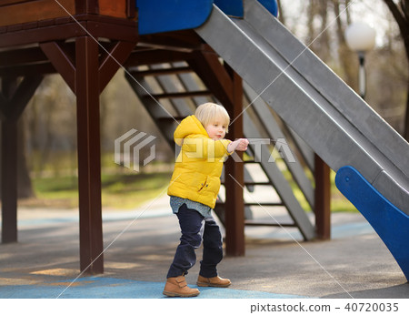 Little boy having fun on outdoor playground on spring or fall day Little boy having fun on outdoor playground on spring or fall day 40720035