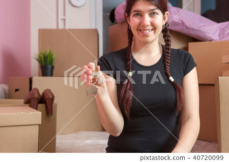 Image of young brunette with keys from apartment against blank wall Image of young brunette with keys from apartment against blank wall 40720099