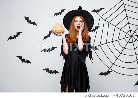 Portrait of beautiful caucasian witch holding pumpkin for celebrating Halloween. 40720168