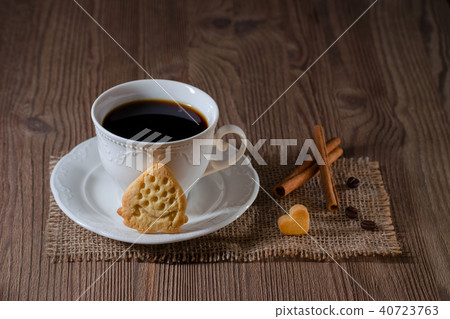 a cup of coffee and cookies like strawberry and heart with cinnamon, coffee beans on wooden table a cup of coffee and cookies like strawberry and heart with cinnamon, coffee beans on wooden table 40723763