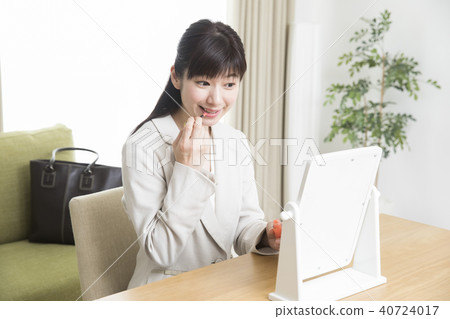 A woman applying lipstick A woman applying lipstick 40724017