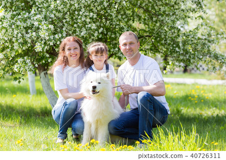 Happy family with a white dog in a summer park. Happy family with a white dog in a summer park. 40726311