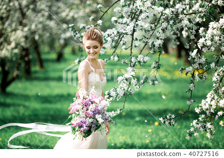 Beautiful girl hands with a branch of a blossoming apple tree. Young beautiful blonde woman in 40727516