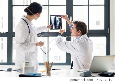 Experienced orthopedist helping his colleague Experienced orthopedist helping his colleague 40727919