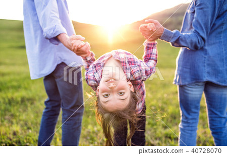 A small girl with her senior grandparents having fun outside in nature at sunset. 40728070