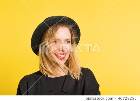 Portrait of a young beautiful woman with black hat in studio on a yellow background. Portrait of a young beautiful woman with black hat in studio on a yellow background. 40728255