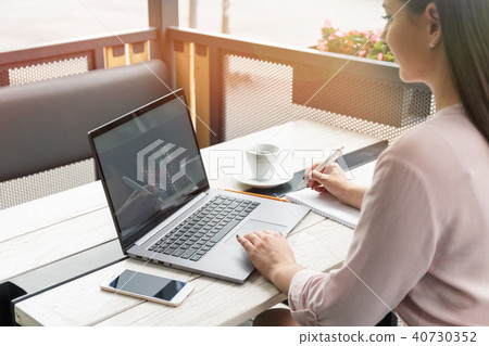 Close up portrait of a young woman working on laptop and writing, coffee on the table. Close up portrait of a young woman working on laptop and writing, coffee on the table. 40730352