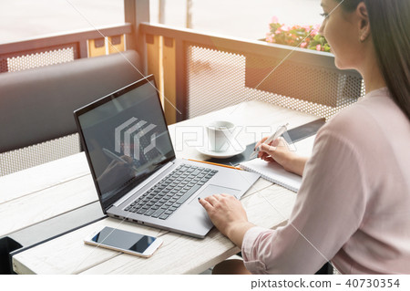 Close up portrait of a young woman working on laptop and writing, coffee on the table. Close up portrait of a young woman working on laptop and writing, coffee on the table. 40730354