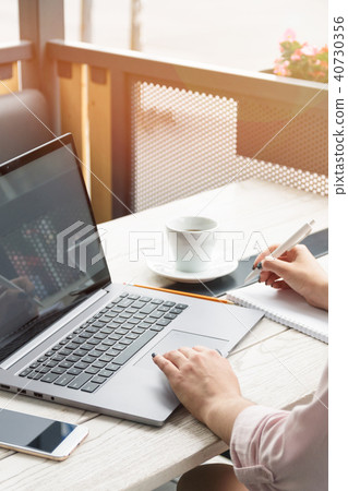 Close up portrait of a young woman working on laptop and writing, coffee on the table. Close up portrait of a young woman working on laptop and writing, coffee on the table. 40730356