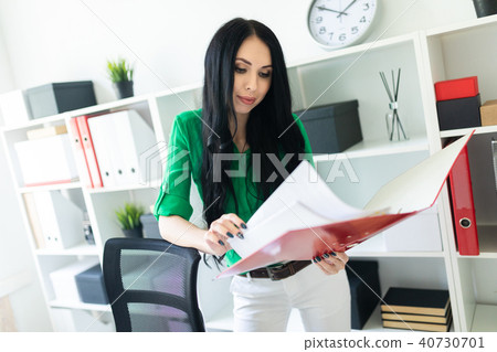A young girl in the office is holding a folder with documents. A young girl in the office is holding a folder with documents. 40730701
