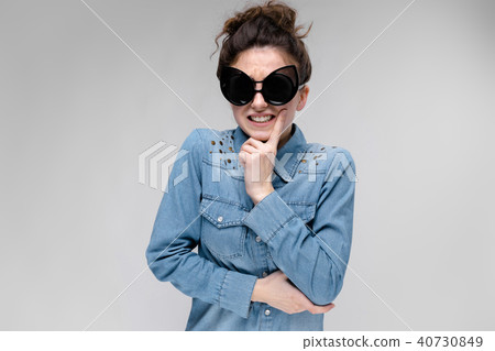 Young brunette girl in black glasses. Cat glasses. The hair is gathered in a bun. The girl holds her 40730849