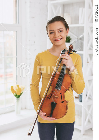 Pleased young female showing her violin Pleased young female showing her violin 40732011