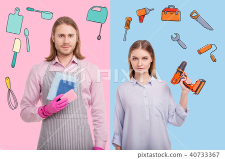 Confident woman holding a drill while her husband standing with washups 40733367