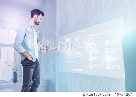 Young web developer touching a futuristic screen while working at home Young web developer touching a futuristic screen while working at home 40734264