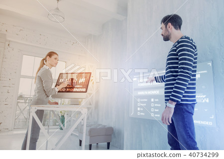 Clever programmer pointing to the screen while talking to his colleague Clever programmer pointing to the screen while talking to his colleague 40734299