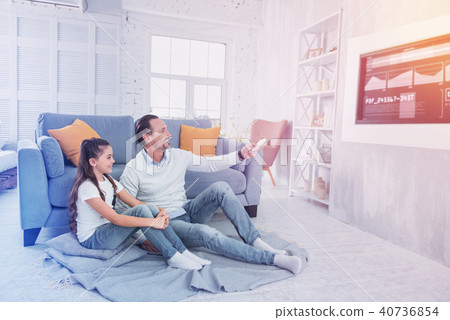 Cheerful father smiling while watching TV with his daughter 40736854