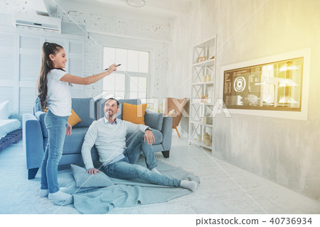 Smiling girl standing with a stylus and her father looking at her Smiling girl standing with a stylus and her father looking at her 40736934