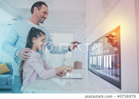 Cheerful man holding a stylus and his daughter using a modern tablet 40736979