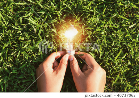 hand holding light bulb on grass with sunset 40737062