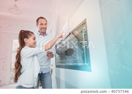 Cheerful man smiling while his clever daughter using a modern device 40737346