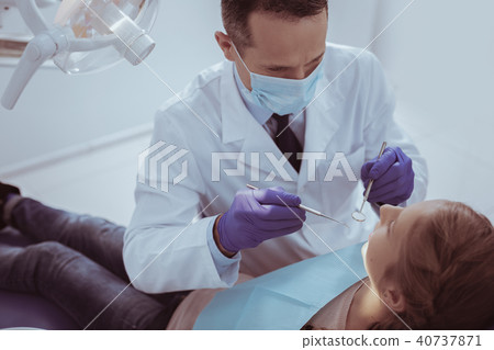 Confident male dentist conducting checkup 40737871