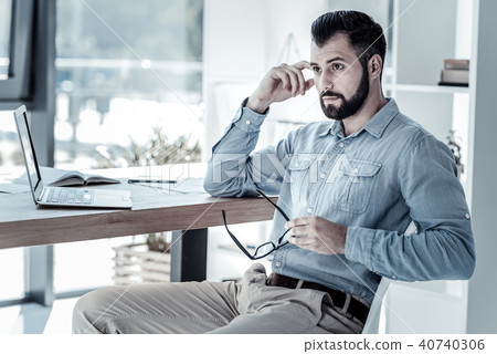 Thoughtful concentrated man looking aside holding hand near head. 40740306