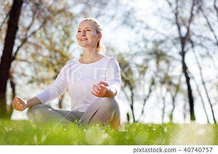 Cheerful delighted woman sitting in the grass 40740757