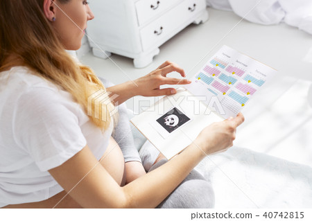 Serious pregnant woman checking pregnancy diary 40742815