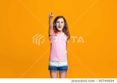 The happy teen girl pointing to you, half length closeup portrait on orange background. The happy teen girl pointing to you, half length closeup portrait on orange background. 40744684