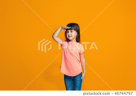 The happy teen girl standing and smiling against orange background. The happy teen girl standing and smiling against orange background. 40744797
