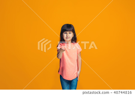 The happy teen girl standing and smiling against orange background. The happy teen girl standing and smiling against orange background. 40744816