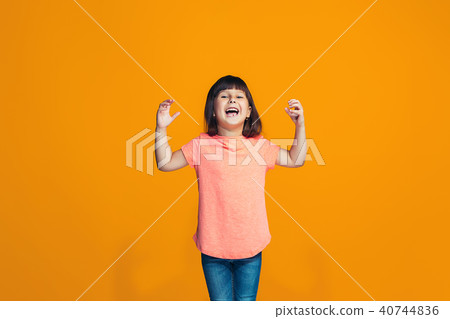 The happy teen girl standing and smiling against orange background. The happy teen girl standing and smiling against orange background. 40744836