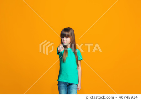 The happy teen girl pointing to you, half length closeup portrait on orange background. 40748914
