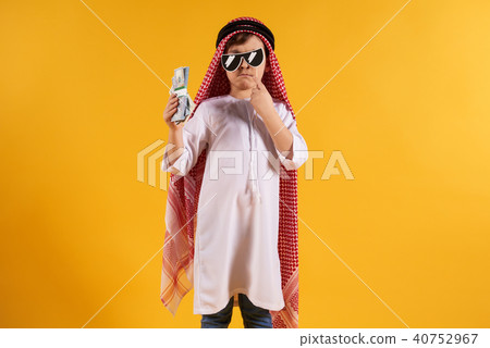 Arabian boy in keffiyeh holds bundle of dollars 40752967