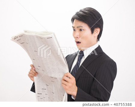 Surprised businessman looking at newspaper stock column Surprised businessman looking at newspaper stock column 40755388