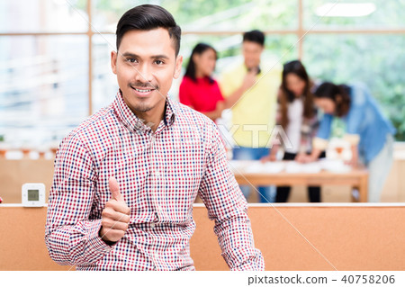 Portrait of young confident Asian employee showing thumb up Portrait of young confident Asian employee showing thumb up 40758206