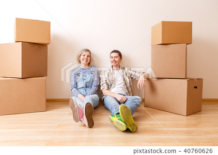 Photo of young married couple sitting on floor among cardboard boxes Photo of young married couple sitting on floor among cardboard boxes 40760626