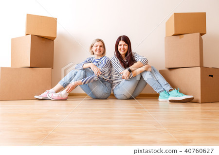 Photo of two girls sitting on floor among cardboard boxes Photo of two girls sitting on floor among cardboard boxes 40760627
