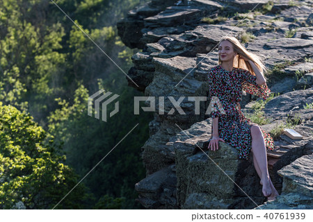 Beautiful girl in dress sits on rock in nature 40761939