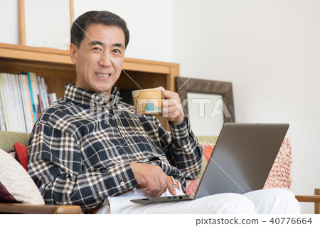 中間男性觀看個人計算機在客廳 中間男性觀看個人計算機在客廳 40776664