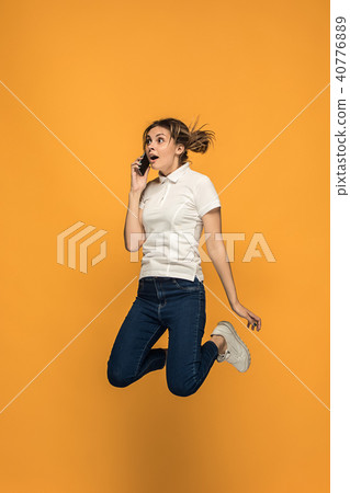 Full length of pretty young woman with mobile phone while jumping Full length of pretty young woman with mobile phone while jumping 40776889