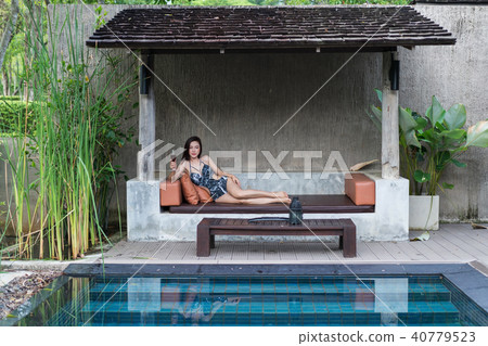 woman on chair and holding a glass in swimming pool woman on chair and holding a glass in swimming pool 40779523
