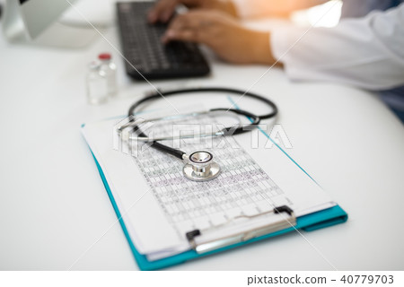 Stethoscope with Doctor working on desk computer Stethoscope with Doctor working on desk computer 40779703