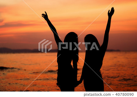 Silhouette of two woman having fun on the sea beach Silhouette of two woman having fun on the sea beach 40780090