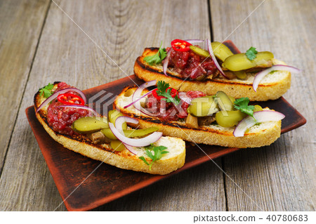 Pickled gherkin and salmon bruschettas on table 40780683