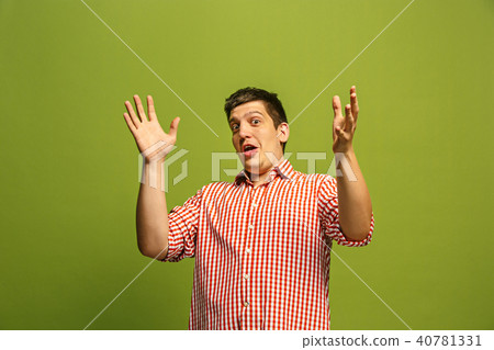 The young attractive man looking suprised isolated on green 40781331