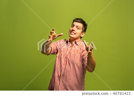 The young emotional angry man screaming on green studio background The young emotional angry man screaming on green studio background 40781421