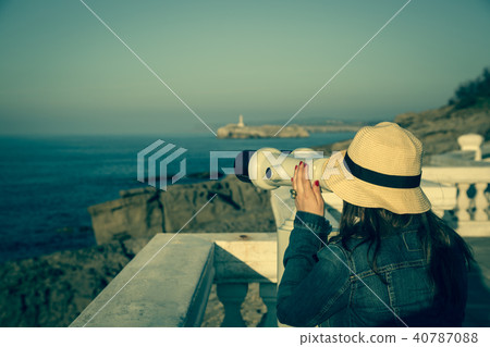 Young girl looking through a coin operated 40787088