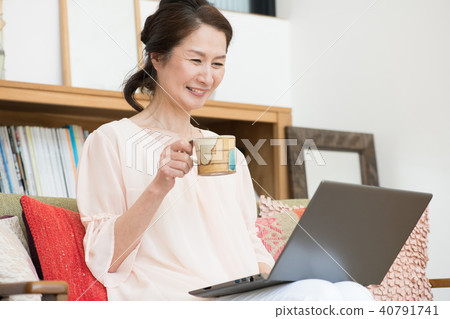 中間女性觀看個人計算機在客廳 40791741